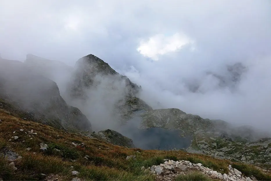 Photo source: bg.wikipedia.org  If you love nature and dream of admiring the views of ancient forests, snow-capped peaks and endless blue lakes, we offer you a short trip to one of the most beautiful lakes in our country - Elenino Lake. Where is? Elenino Lake is located in the Rila Mountains and is the largest of the three lakes that form a lake group called Elena Lakes.  The lake is located at 2479 meters above sea level, and in its waters are reflected four of the most beautiful peaks in Rila - Orlovets, Malyovitsa, Popova Kapa and Golyam Kupen.  In terms of size, the lake can hardly be ranked among the largest lakes in the mountain, but with its length of 220 meters, width of 62 meters and depth of up to 5 meters is the largest and most beautiful of the three Elena lakes.  Its shape is slightly elongated and irregular, and its shores are rocky. The lake is filled mainly by the melted snow.   Photo source: bg.wikipedia.org Legend of the lake Like almost all of the natural attractions, Elenino Lake has its own beautiful and very romantic legend. According to the story, many years ago, during the Turkish slavery, in Samokov lived a wonderfully beautiful girl named Elena.  One day the Turkish pasha Selim came to visit the town, there he saw Elena and asked the residents of Samokov to sell him the beautiful girl or otherwise he was going to take their property.  The headmans came together and did not think much, but sold the girl to Selim Pasha. However, Elena managed to escape while they were on the way to her new home, and she hid at the mountains. There she was met by the detachment of Malyo Voyvoda and the girl became part of his group.  The years passed, and the girl became one of the best archers of the detachment and did not miss a battle with the Turkish troops.  Driven by her desire for revenge, Elena does not allow herself to have feelings, but the heart is hard to command and she fell in love with the flag bearer of the group.  Although the girl loved him with all her heart, she did not confess her feelings to him because she believed that the revenge was more important than love.   Photo source: bg.wikipedia.org  And so one day Elena finally managed to find Selim Pasha and took revenge on him. She killed the Turk with a precision shot, but unfortunately during the shooting she was badly hurt.  Her partners, who saw that she was getting weaker and would not survive, took her high in the mountains and laid her on the shore of one of the most beautiful and clear lakes.  With the last of her strength, Elena finally confessed her love to her beloved and realized that because of the revenge she had lost the most important and valuable thing in life - her love.  After her death, Elena was buried on the shores of the lake, and it has been named after her ever since - Elenino Lake.   Photo source: luckybansko.bg How do you get there? As the lake is located on the way of the tourist trail for climbing Malyovitsa peak, the only way to reach it is to take the route. Route of Malyovitsa CMS - Malyovitsa peak  The route starts from Malyovitsa CMS in the Mecha Polyana area (about 20 km from Samokov).  You can reach the area by car, which you must leave in the parking lot in front of the CMS "Malyovitsa" and walk along the trail.   Photo source: bg.wikipedia.org   Stage 1 - Malyovitsa CMS - Malyovitsa hut  The distance from the center to the hut at a moderate pace and without much need for rest is about 35 - 40 minutes.  The path you have to follow is marked with blue and there are no forks, so there is nowhere to go wrong.  This stage of the route is of low difficulty and with a relatively small slope, so even if you are not one of the best prepared hikers, you won’t find it difficult.   Photo source: bg.wikipedia.org  Stage 2 - Malyovitsa hut - First and Second terrace  If you get to the hut, it is good to eat, relax and most of all do not forget to refill with water, because the steep slope starts up and there is no place to pour water.  After Malyovitsa hut you should follow the path marked with white & blue. The ascent becomes more difficult as the vegetation gradually decreases and the displacement increases little by little.  About half an hour after the hut you will reach the first terrace of the trail, where you can take another short break to relax and enjoy the views that will unfold in front of your eyes.  The ascent continues to the Second Terrace. The path you have to follow is now marked in red, but even if you don't pay much attention, you can't go wrong, as this is the only path that leads to Malyovitsa. The route to the Second Terrace has an acceptable slope, but the path becomes more and more rocky and there is almost no vegetation.  You will know that you have passed the Second Terrace when you see a large rock with memorial plaques placed on it. (Memorial plaques of Bulgarian climbers who died while climbing native and foreign peaks).   Photo source: bg.wikipedia.org   Stage 3 - Second terrace - Elenino Lake  If you decide to reach only Elenino Lake and not finish the trail by climbing Malyovitsa Peak, you don’t have a much transition left.  From the Second Terrace you will reach Elenino Lake in about an hour if you walk at a medium pace. You have to be more careful here, because the displacement is quite large, the path is extremely rocky, and there are several super steep places, so if you are not careful you can slip.  But if you manage to cope, we assure you, the moment you see the beautiful lake you will forget the exhaustion and fatigue.   Photo source: wikimapia.org   If you still have the strength after a 3 hours of walking and decide to make a little more effort and conquer the peak, you have to overcome only one more stage of the route.  Stage 4 - Elenino Lake - Malyovitsa Peak  In the beginning the ascent to the top is quite difficult, as the terrain has a large displacement and is very rocky. Fortunately, the steep area is not big and after overcoming it you will have to walk along the ridge of the mountain, where the terrain is flat and the views are amazing.    Photo source: bg.wikipedia.org  If you turn around and look back, you will see the whole group of Elena lakes, and if you look at the distant valley to the south you will see the Rila Monastery.  In about 30 minutes of climbing with medium difficulty you will reach your final destination - peak Malyovitsa. In front of you will be an incredible view of Mount Musala, the Ribnovo Lake, and if it is sunny and clear you can see in the distance Pirin and even Vitosha Mountains.