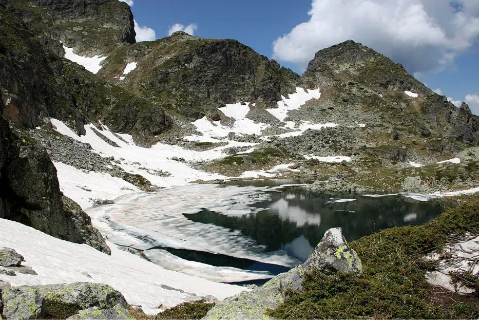 Photo source: bg.wikipedia.org  If you love nature and dream of admiring the views of ancient forests, snow-capped peaks and endless blue lakes, we offer you a short trip to one of the most beautiful lakes in our country - Elenino Lake. Where is? Elenino Lake is located in the Rila Mountains and is the largest of the three lakes that form a lake group called Elena Lakes.  The lake is located at 2479 meters above sea level, and in its waters are reflected four of the most beautiful peaks in Rila - Orlovets, Malyovitsa, Popova Kapa and Golyam Kupen.  In terms of size, the lake can hardly be ranked among the largest lakes in the mountain, but with its length of 220 meters, width of 62 meters and depth of up to 5 meters is the largest and most beautiful of the three Elena lakes.  Its shape is slightly elongated and irregular, and its shores are rocky. The lake is filled mainly by the melted snow.   Photo source: bg.wikipedia.org Legend of the lake Like almost all of the natural attractions, Elenino Lake has its own beautiful and very romantic legend. According to the story, many years ago, during the Turkish slavery, in Samokov lived a wonderfully beautiful girl named Elena.  One day the Turkish pasha Selim came to visit the town, there he saw Elena and asked the residents of Samokov to sell him the beautiful girl or otherwise he was going to take their property.  The headmans came together and did not think much, but sold the girl to Selim Pasha. However, Elena managed to escape while they were on the way to her new home, and she hid at the mountains. There she was met by the detachment of Malyo Voyvoda and the girl became part of his group.  The years passed, and the girl became one of the best archers of the detachment and did not miss a battle with the Turkish troops.  Driven by her desire for revenge, Elena does not allow herself to have feelings, but the heart is hard to command and she fell in love with the flag bearer of the group.  Although the girl loved him with all her heart, she did not confess her feelings to him because she believed that the revenge was more important than love.   Photo source: bg.wikipedia.org  And so one day Elena finally managed to find Selim Pasha and took revenge on him. She killed the Turk with a precision shot, but unfortunately during the shooting she was badly hurt.  Her partners, who saw that she was getting weaker and would not survive, took her high in the mountains and laid her on the shore of one of the most beautiful and clear lakes.  With the last of her strength, Elena finally confessed her love to her beloved and realized that because of the revenge she had lost the most important and valuable thing in life - her love.  After her death, Elena was buried on the shores of the lake, and it has been named after her ever since - Elenino Lake.   Photo source: luckybansko.bg How do you get there? As the lake is located on the way of the tourist trail for climbing Malyovitsa peak, the only way to reach it is to take the route. Route of Malyovitsa CMS - Malyovitsa peak  The route starts from Malyovitsa CMS in the Mecha Polyana area (about 20 km from Samokov).  You can reach the area by car, which you must leave in the parking lot in front of the CMS "Malyovitsa" and walk along the trail.   Photo source: bg.wikipedia.org   Stage 1 - Malyovitsa CMS - Malyovitsa hut  The distance from the center to the hut at a moderate pace and without much need for rest is about 35 - 40 minutes.  The path you have to follow is marked with blue and there are no forks, so there is nowhere to go wrong.  This stage of the route is of low difficulty and with a relatively small slope, so even if you are not one of the best prepared hikers, you won’t find it difficult.   Photo source: bg.wikipedia.org  Stage 2 - Malyovitsa hut - First and Second terrace  If you get to the hut, it is good to eat, relax and most of all do not forget to refill with water, because the steep slope starts up and there is no place to pour water.  After Malyovitsa hut you should follow the path marked with white & blue. The ascent becomes more difficult as the vegetation gradually decreases and the displacement increases little by little.  About half an hour after the hut you will reach the first terrace of the trail, where you can take another short break to relax and enjoy the views that will unfold in front of your eyes.  The ascent continues to the Second Terrace. The path you have to follow is now marked in red, but even if you don't pay much attention, you can't go wrong, as this is the only path that leads to Malyovitsa. The route to the Second Terrace has an acceptable slope, but the path becomes more and more rocky and there is almost no vegetation.  You will know that you have passed the Second Terrace when you see a large rock with memorial plaques placed on it. (Memorial plaques of Bulgarian climbers who died while climbing native and foreign peaks).   Photo source: bg.wikipedia.org   Stage 3 - Second terrace - Elenino Lake  If you decide to reach only Elenino Lake and not finish the trail by climbing Malyovitsa Peak, you don’t have a much transition left.  From the Second Terrace you will reach Elenino Lake in about an hour if you walk at a medium pace. You have to be more careful here, because the displacement is quite large, the path is extremely rocky, and there are several super steep places, so if you are not careful you can slip.  But if you manage to cope, we assure you, the moment you see the beautiful lake you will forget the exhaustion and fatigue.   Photo source: wikimapia.org   If you still have the strength after a 3 hours of walking and decide to make a little more effort and conquer the peak, you have to overcome only one more stage of the route.  Stage 4 - Elenino Lake - Malyovitsa Peak  In the beginning the ascent to the top is quite difficult, as the terrain has a large displacement and is very rocky. Fortunately, the steep area is not big and after overcoming it you will have to walk along the ridge of the mountain, where the terrain is flat and the views are amazing.    Photo source: bg.wikipedia.org  If you turn around and look back, you will see the whole group of Elena lakes, and if you look at the distant valley to the south you will see the Rila Monastery.  In about 30 minutes of climbing with medium difficulty you will reach your final destination - peak Malyovitsa. In front of you will be an incredible view of Mount Musala, the Ribnovo Lake, and if it is sunny and clear you can see in the distance Pirin and even Vitosha Mountains.